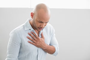 Man with his hand on his chest, from heartburn.
