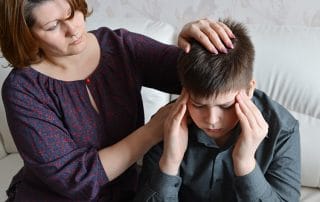 Mother cares for her son who has migraine associated with TMJ. If I teen has TMJ, a study recommends a team treatment approach to improve results. This means that a neurologist should work with a doctor (or dentist) with expertise in orofacial pain. Cutting down the intensity and frequency of TMJ pain could lead to a responsive decrease in the intensity and frequency of migraines.