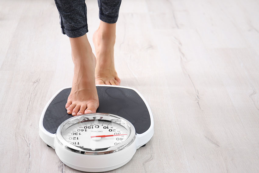 woman beginning to stand on scale to check her weight