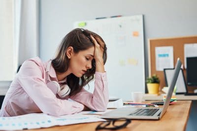 exhausted woman holding her head in pain while at the office